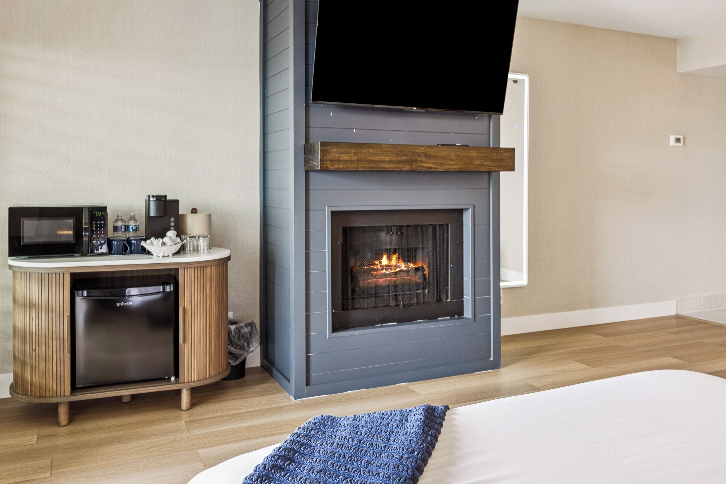 A modern room with a built-in fireplace, a microwave, and a small refrigerator.