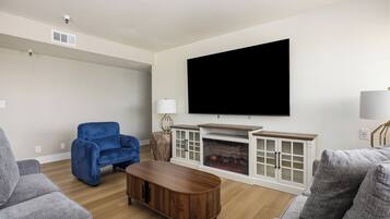 Una sala de estar con chimenea, un televisor de pantalla plana y un sillón azul.