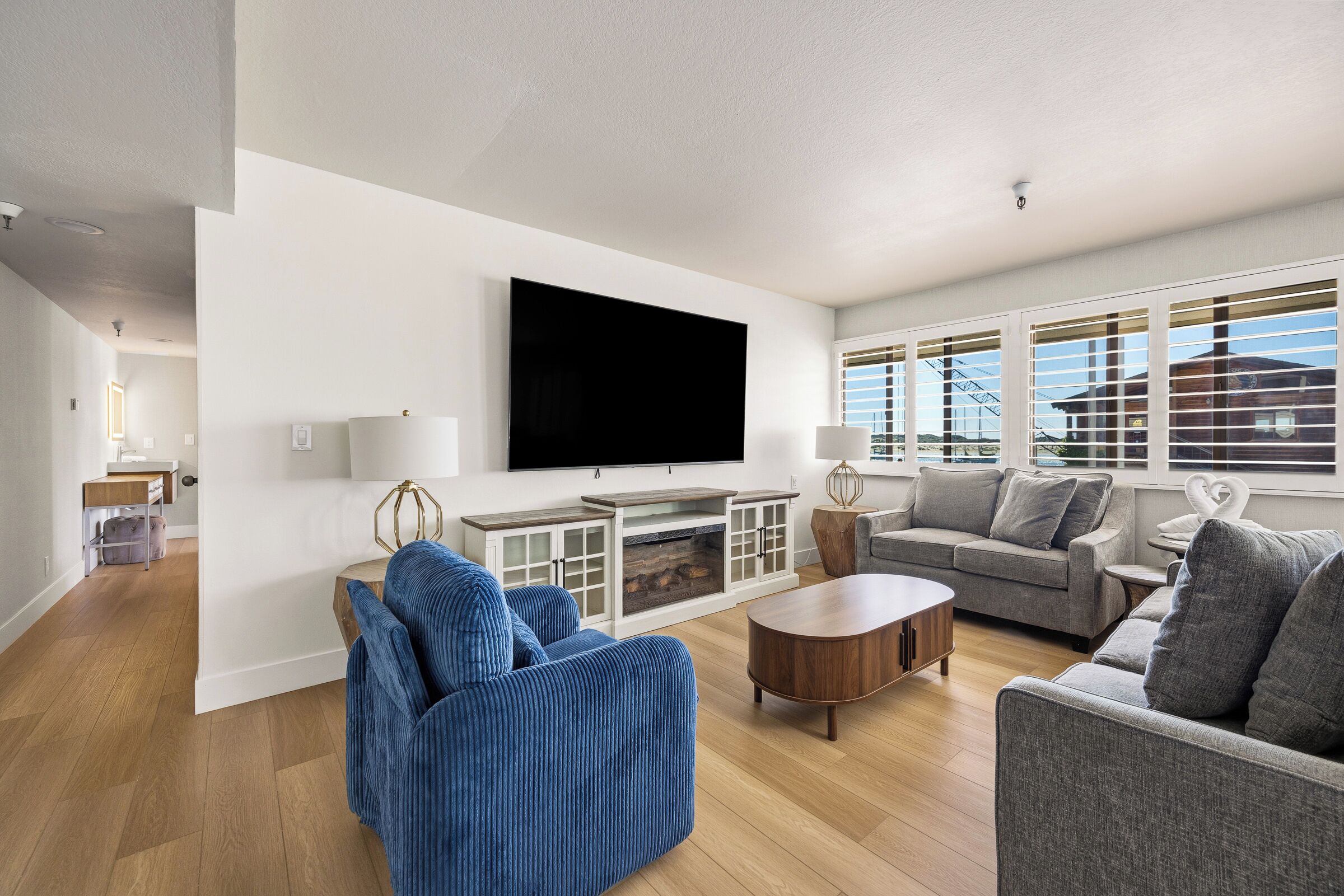 A modern living room with a flat-screen TV, two sofas, a coffee table, and a fireplace.