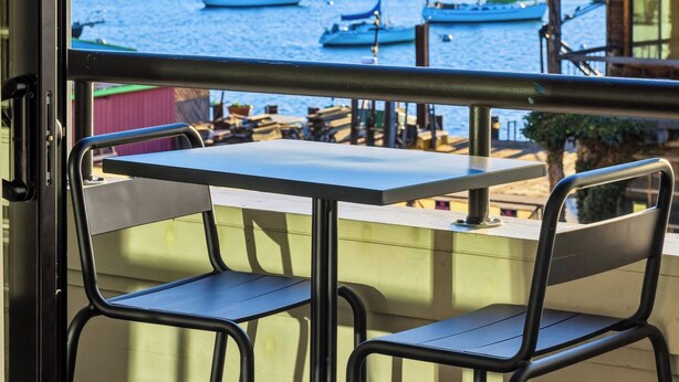 A balcony with a view of boats and a sandy beach. - 456 Embarcadero Inn & Suites (Morro Bay)