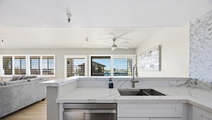 A modern kitchen with a built-in dishwasher, white cabinetry, and a view to the outside. - 456 Embarcadero Inn & Suites (Morro Bay)