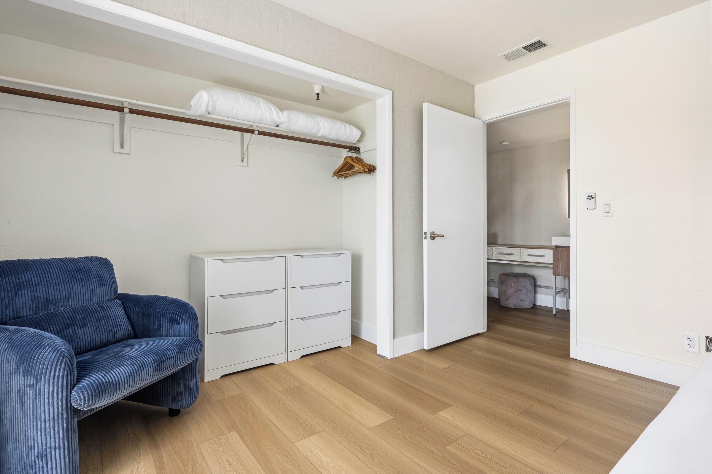 A bedroom with a bed, a wardrobe, a dresser, and a blue sofa.