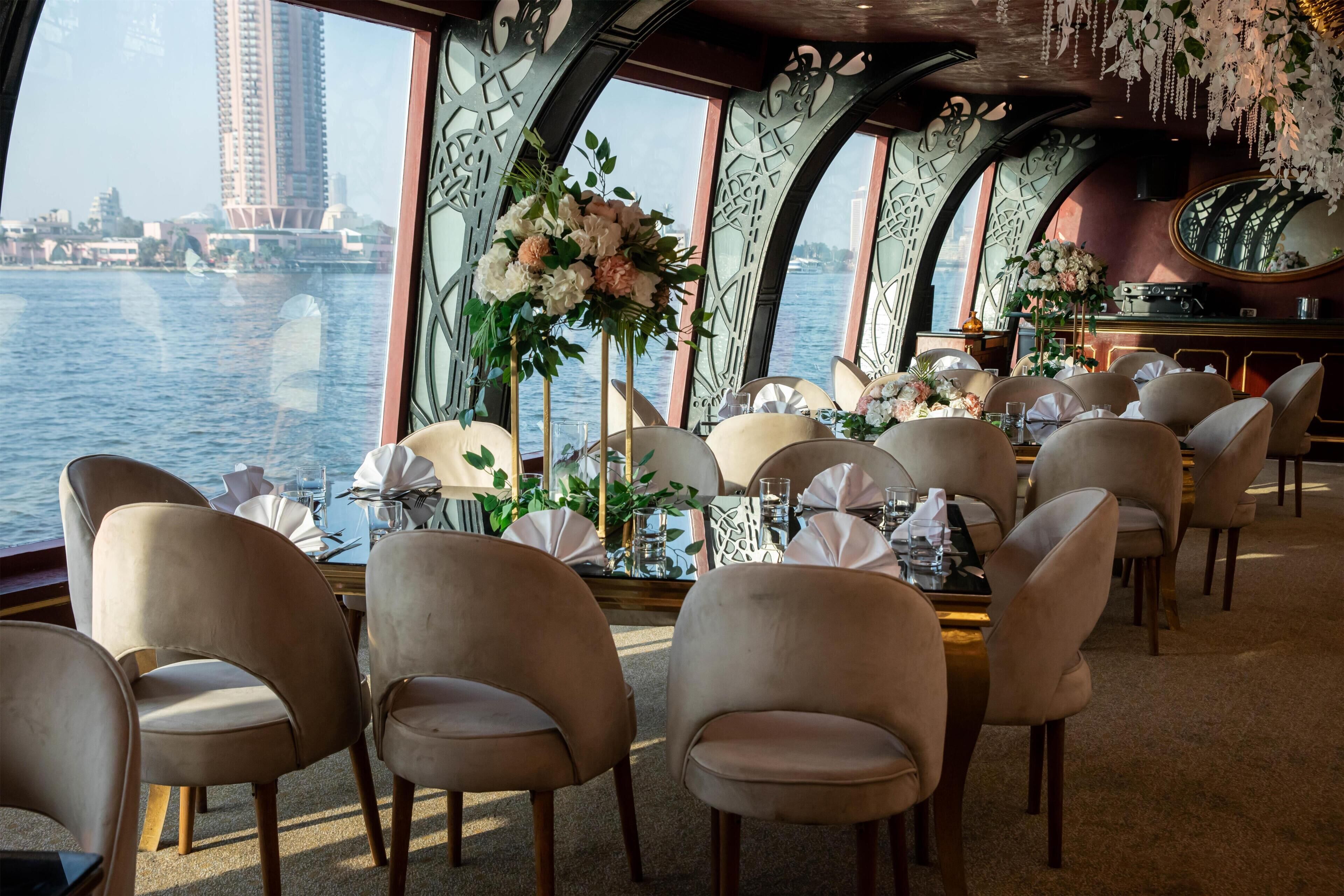 Comedor con mesas dispuestas para el servicio, sillas y flores decorativas.