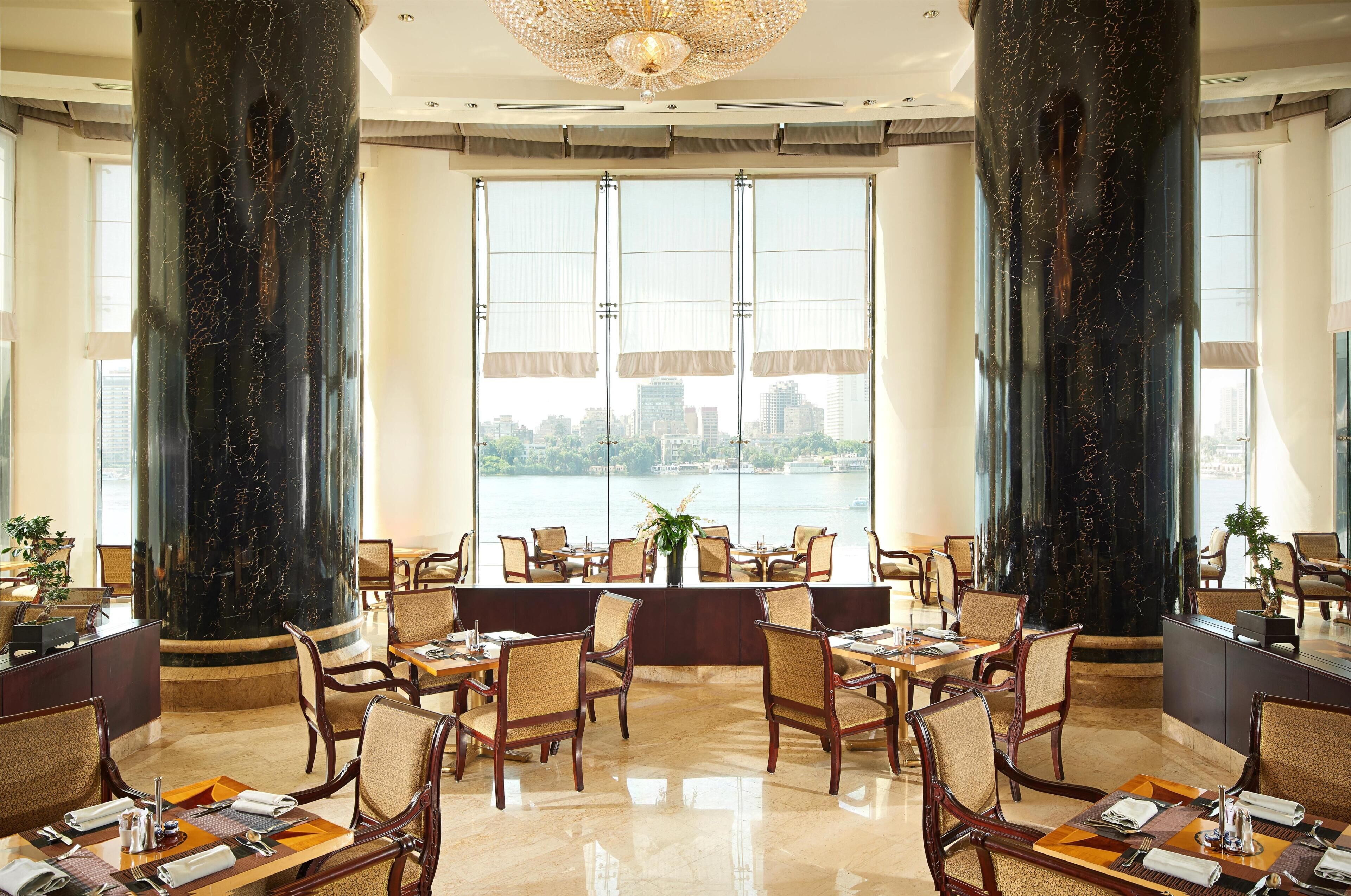 Un comedor espacioso con techos altos, ventanas amplias y vistas a un paisaje urbano.