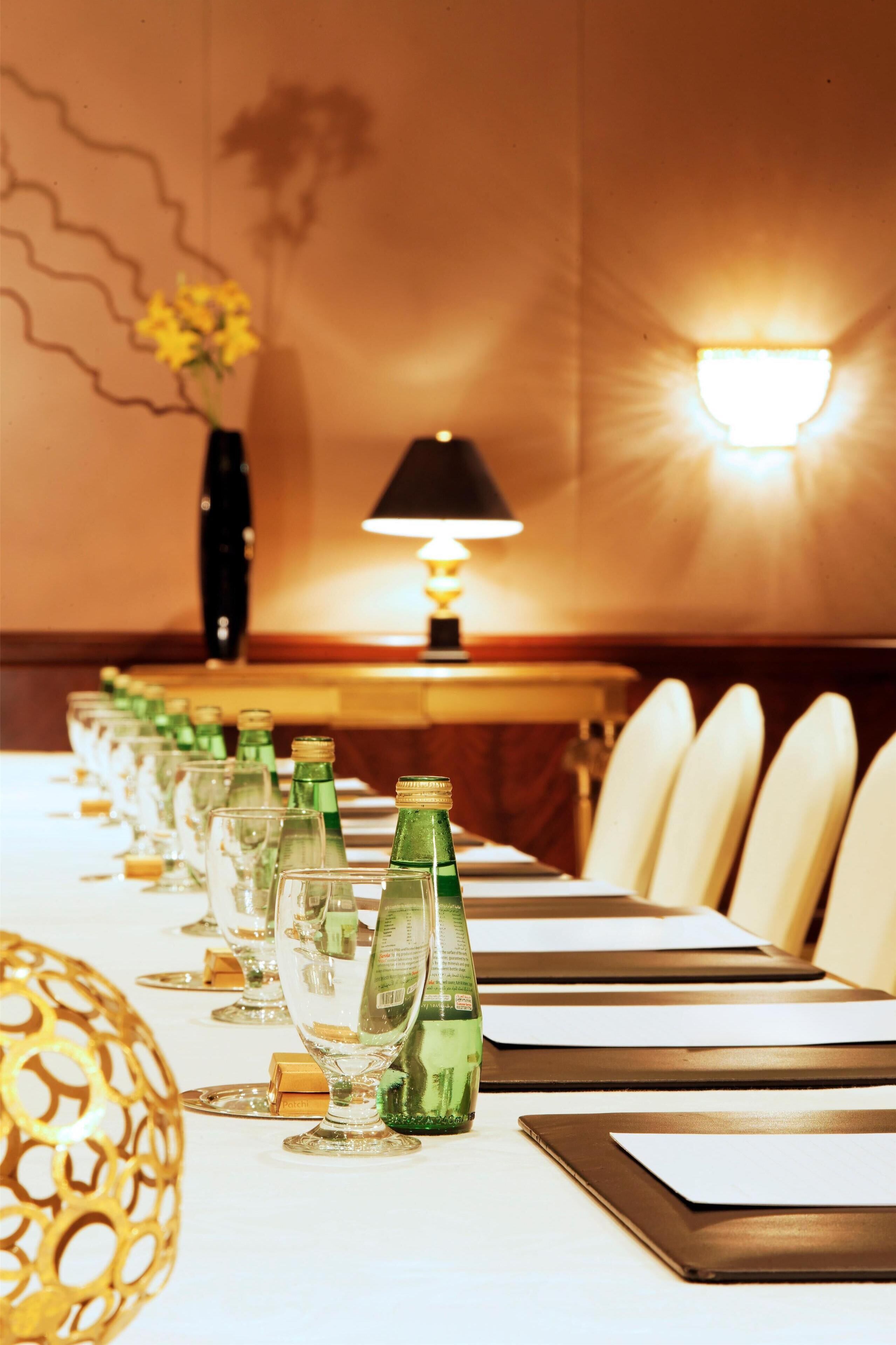 A hotel dining table set with glasses, bottles, and place settings.