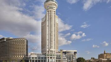 A tall hotel with a cylindrical tower, a waterfront location, and a modern architectural design.