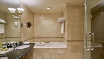 A modern bathroom with two sinks, a bathtub, a glass shower enclosure, and a vanity mirror.