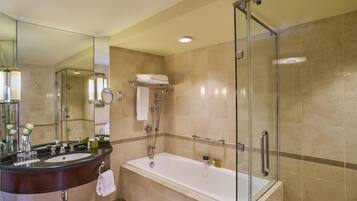 A modern bathroom with a glass-enclosed shower, a large bathtub, a vanity with a mirror, and a towel rack.