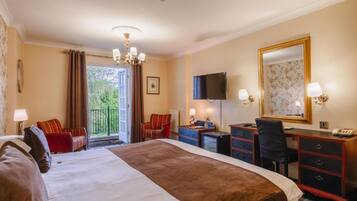 A hotel room with a large bed, a desk, a chair, a television, and a balcony with curtains.