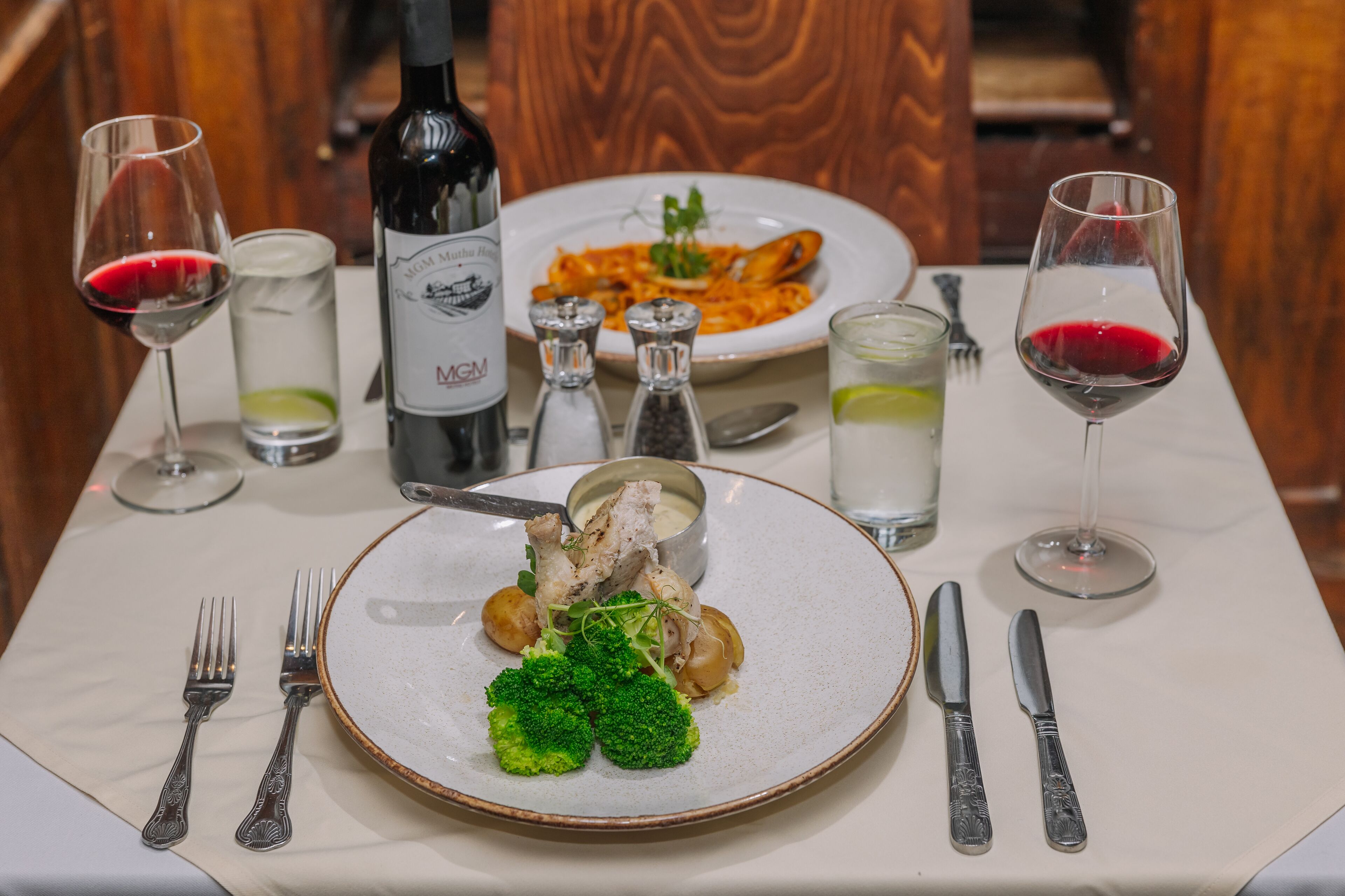 A dining table set with plates of food, wine glasses, and cutlery.