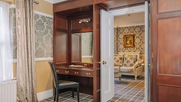 A room with a wooden desk, a chair, a door, and a patterned carpet.