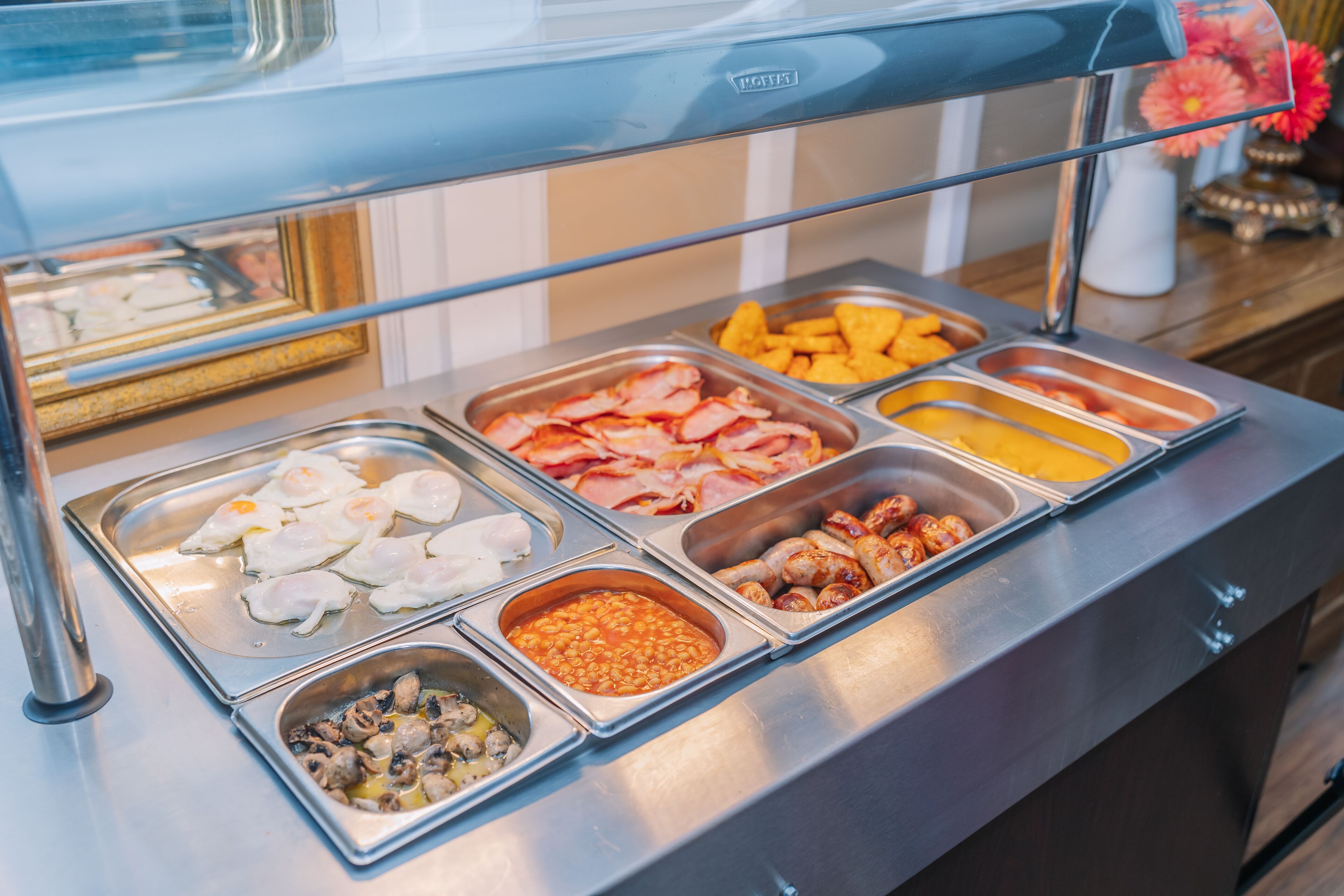 A buffet with various food options including eggs, bacon, sausages, and beans.