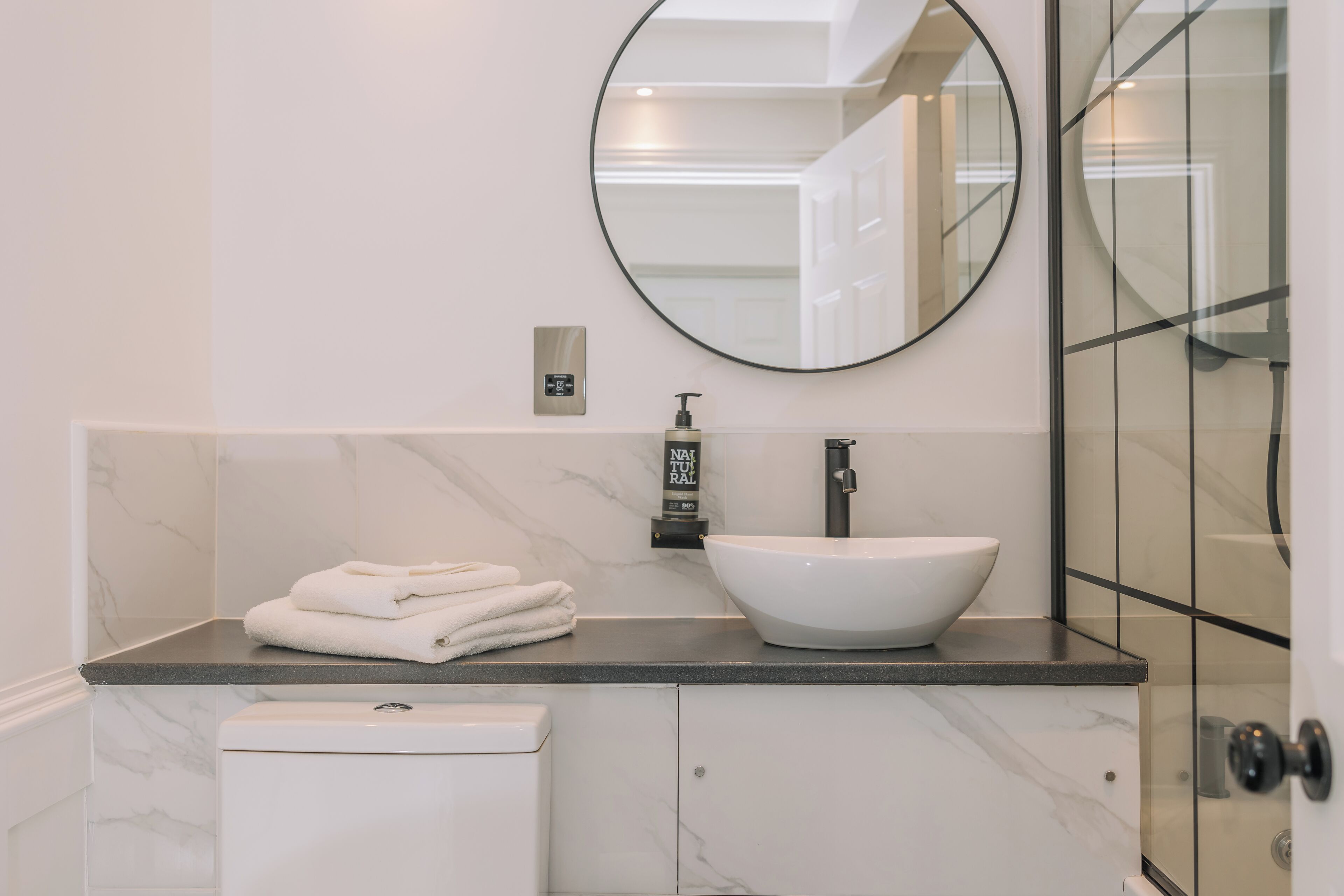 Un bagno con un lavabo in marmo bianco, uno specchio grande e un portasciugamani.