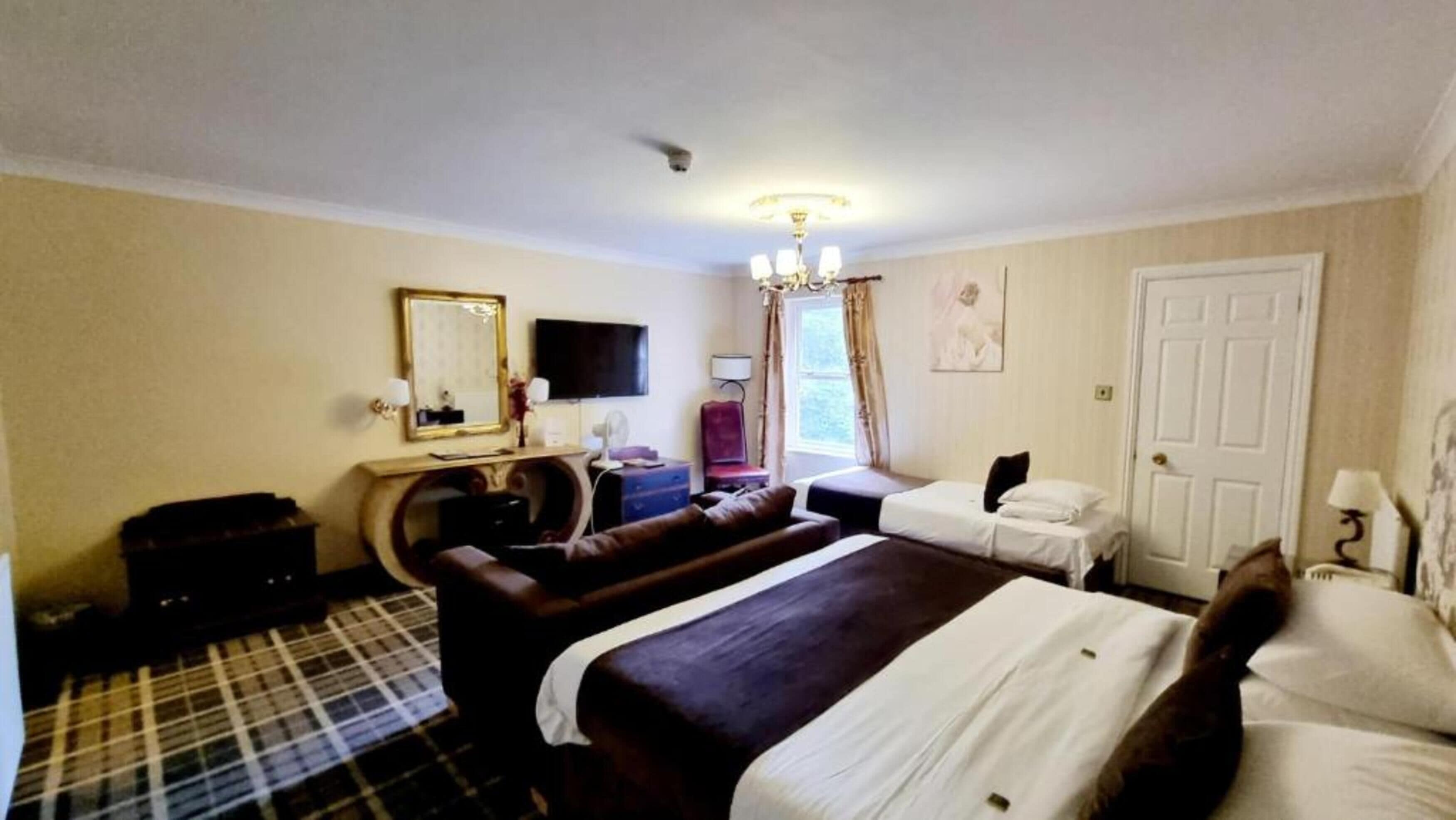 Hotelkamer met twee bedden, een grote spiegel, een flatscreen televisie, een bureau met lamp en een ruitvast tapijt.