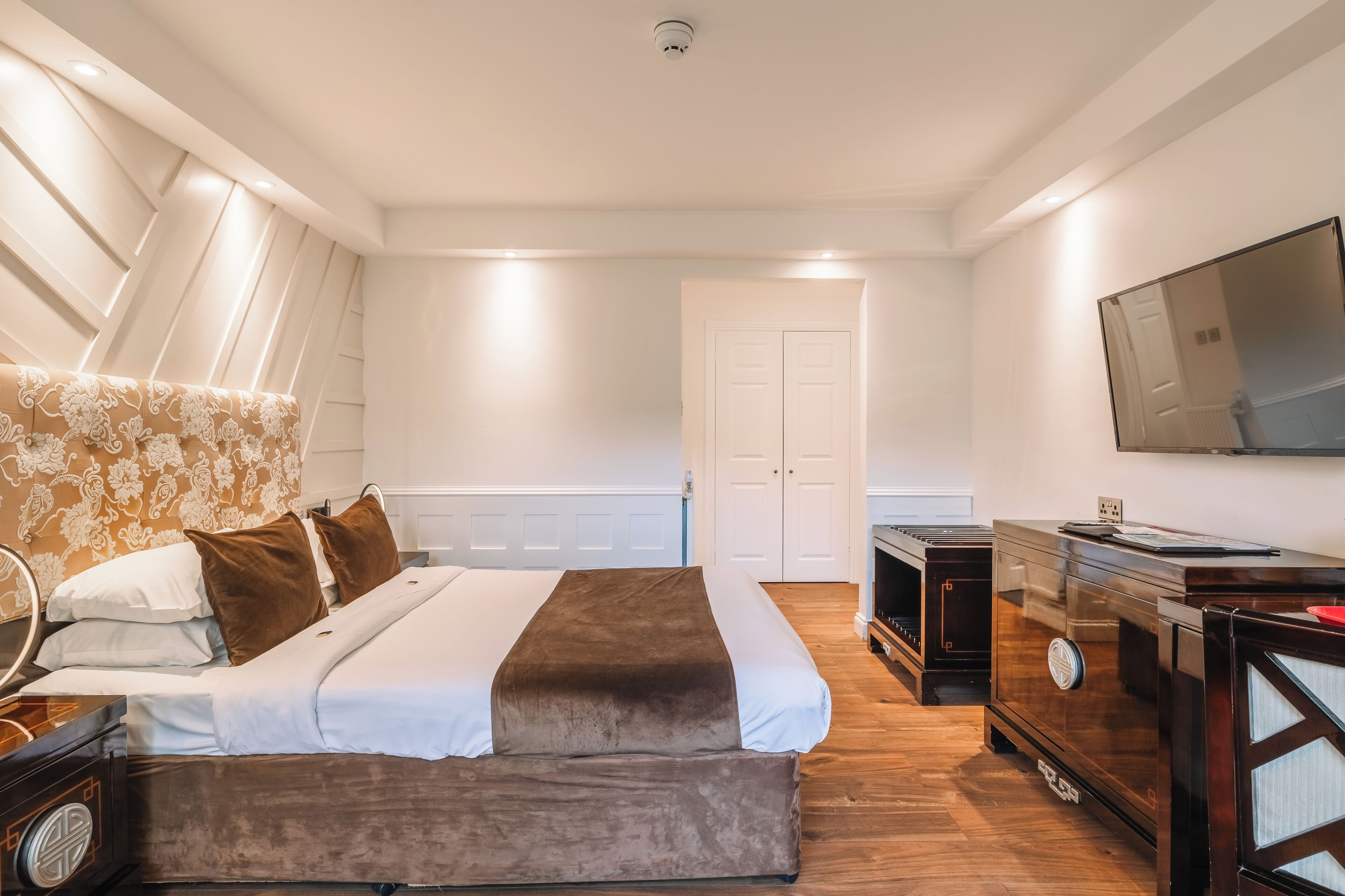 A bedroom with a bed, a dresser, a TV, and a door.