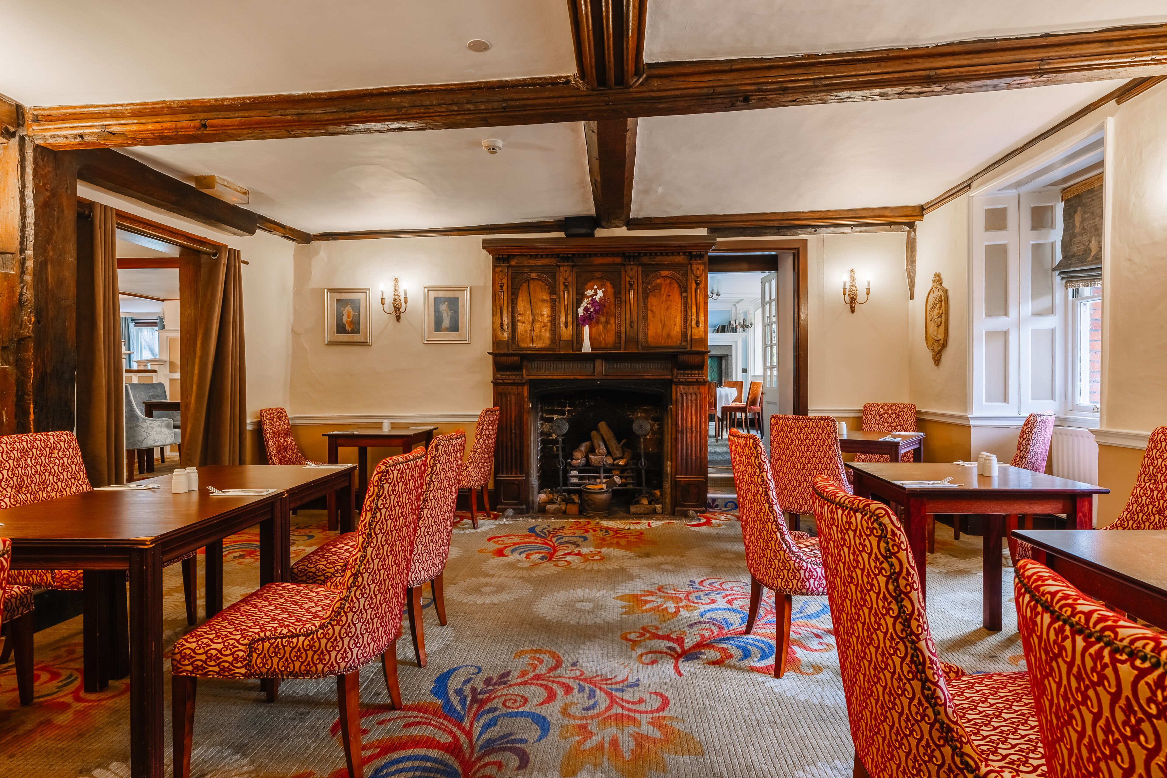 A conference room with wooden tables and chairs, a fireplace, and a patterned carpet.