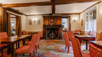 A conference room with wooden tables and chairs, a fireplace, and a patterned carpet.
