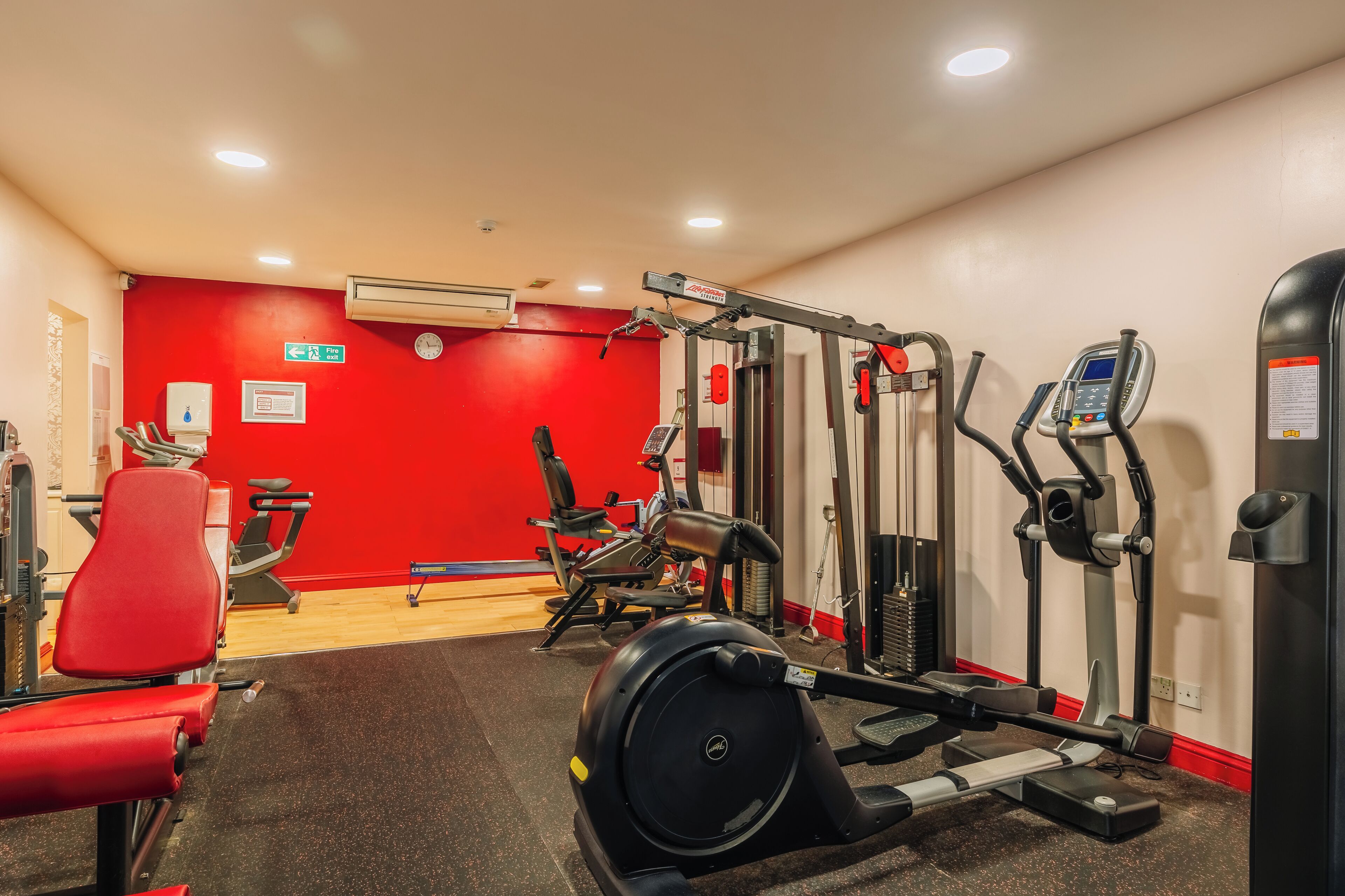 Ett gym med olika typer av träningsutrustning, inklusive löpband, motionscyklar och styrketräningsmaskiner.