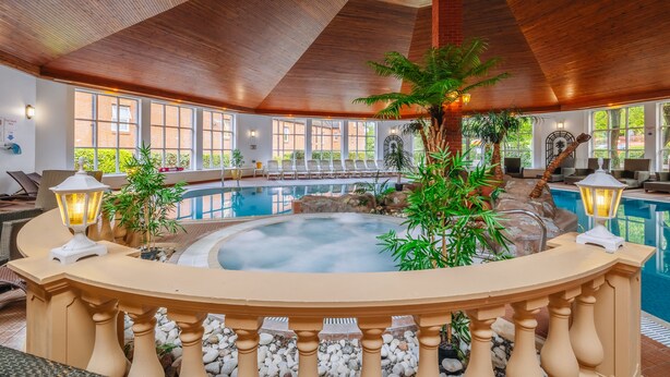 A spa area with a hot tub, lounge chairs, and a wooden ceiling. - Muthu Belstead Brook Hotel (Ipswich)