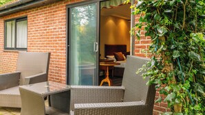 A brick house with a sliding glass door leading to a bedroom. There are wicker chairs and a small table outside. - Muthu Belstead Brook Hotel (Ipswich)