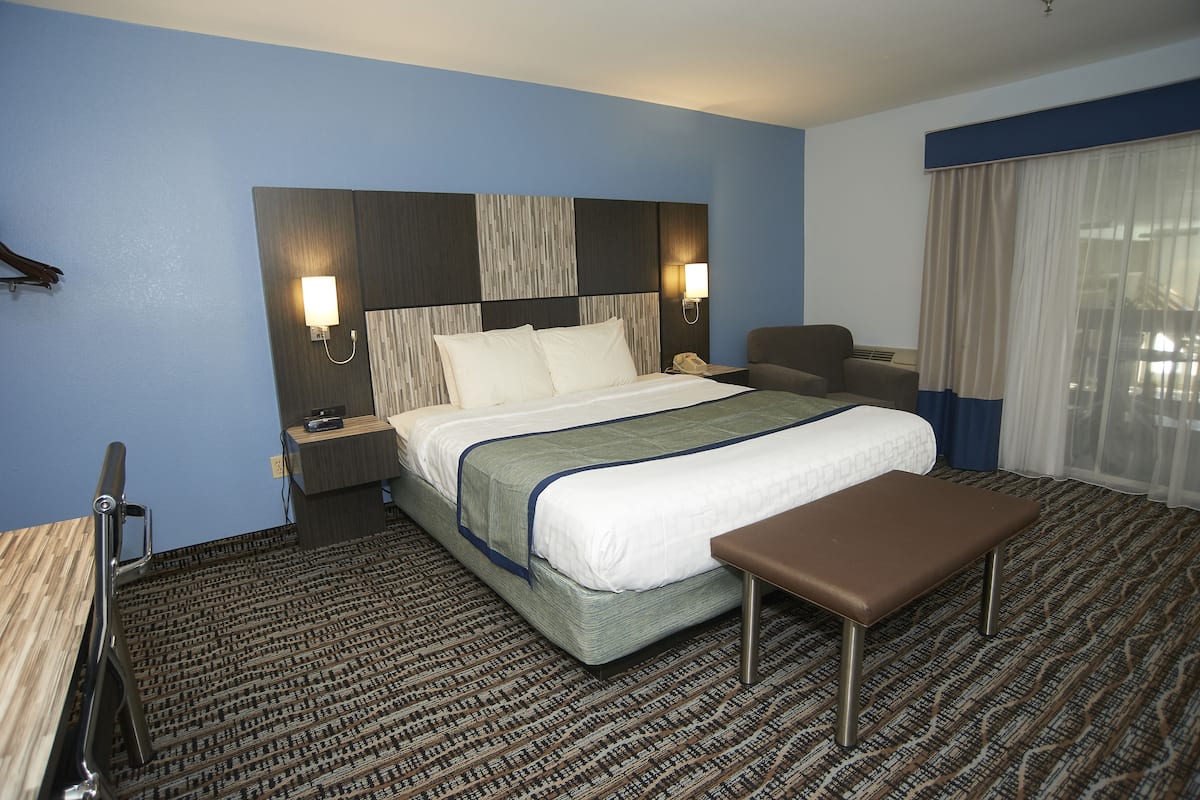 A hotel room with a large bed, a bench, a desk, and a chair.