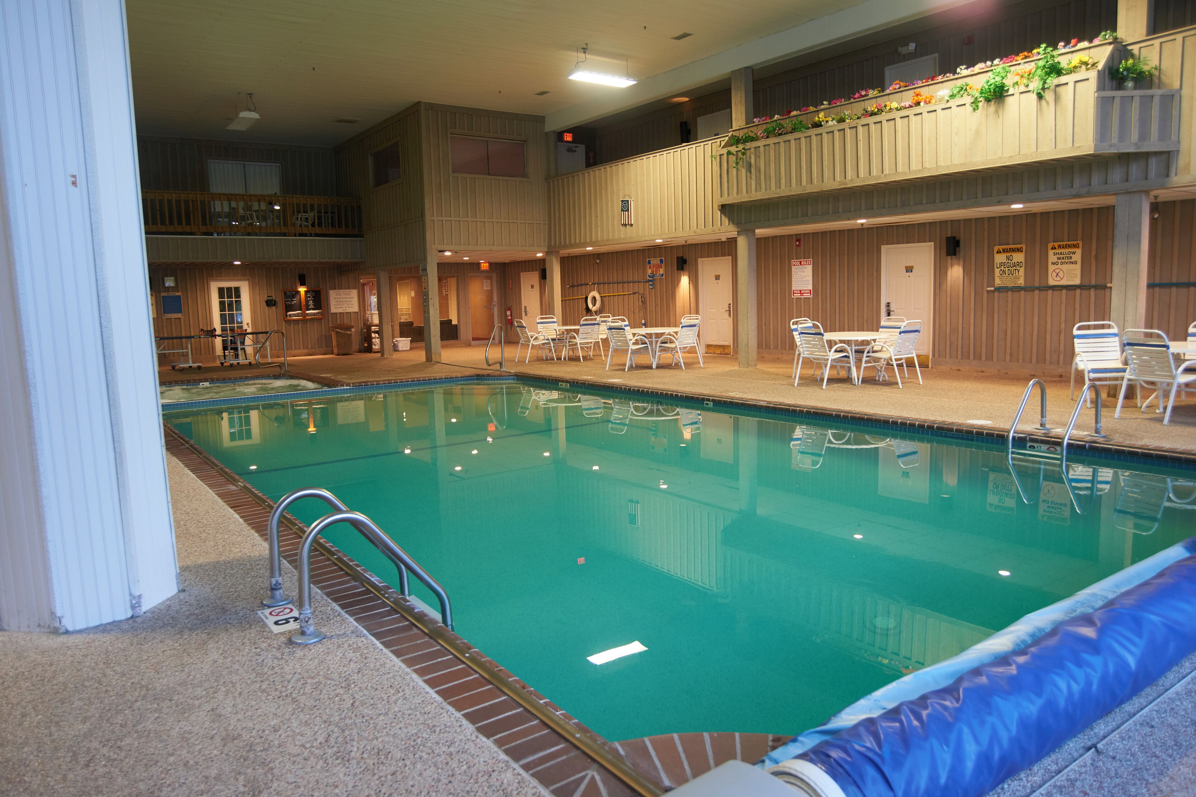 Una piscina interior con varios niveles, zonas de estar y un balcón cubierto con plantas.