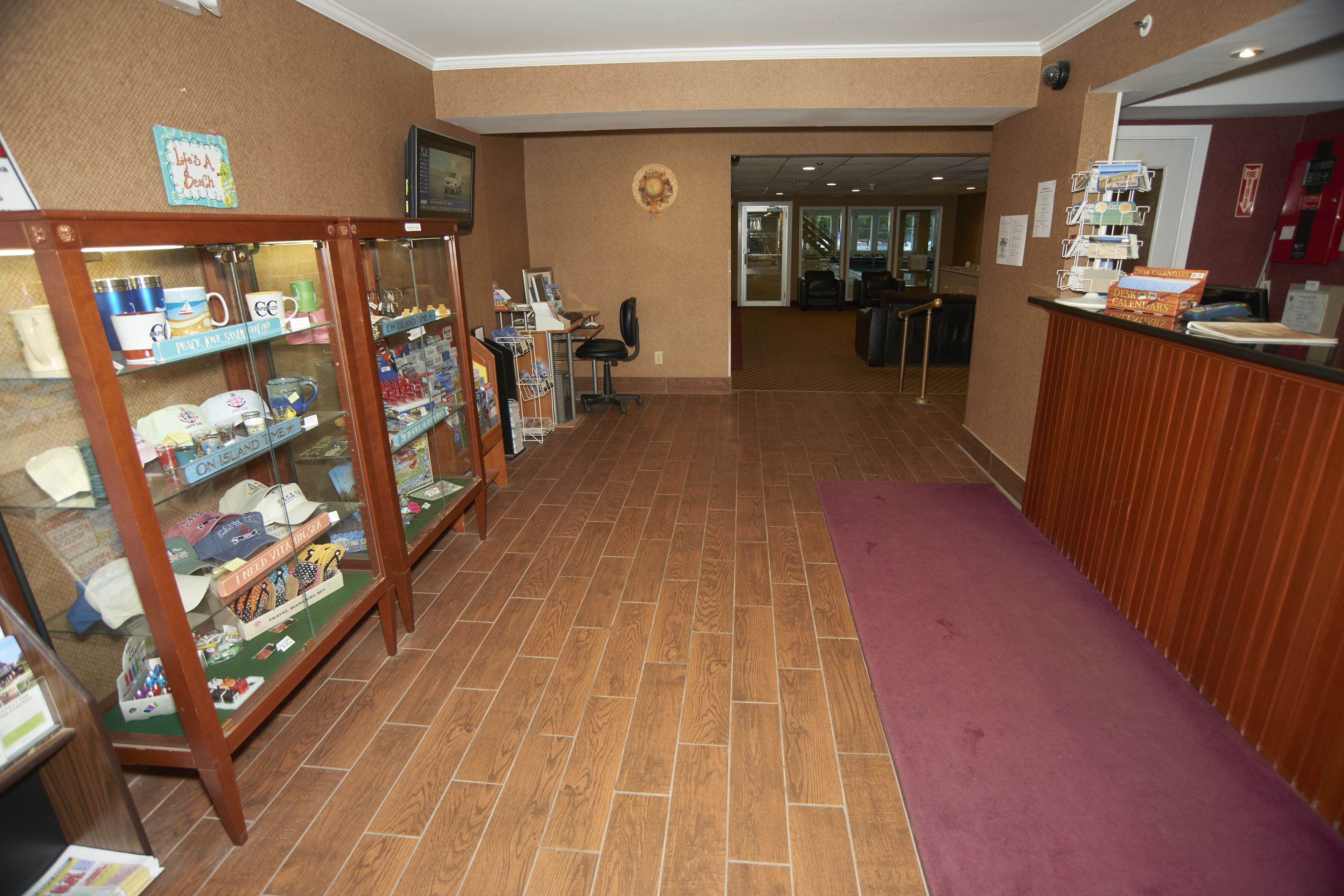 A reception area with a wooden reception desk, a glass display case with souvenirs, and a purple carpet.