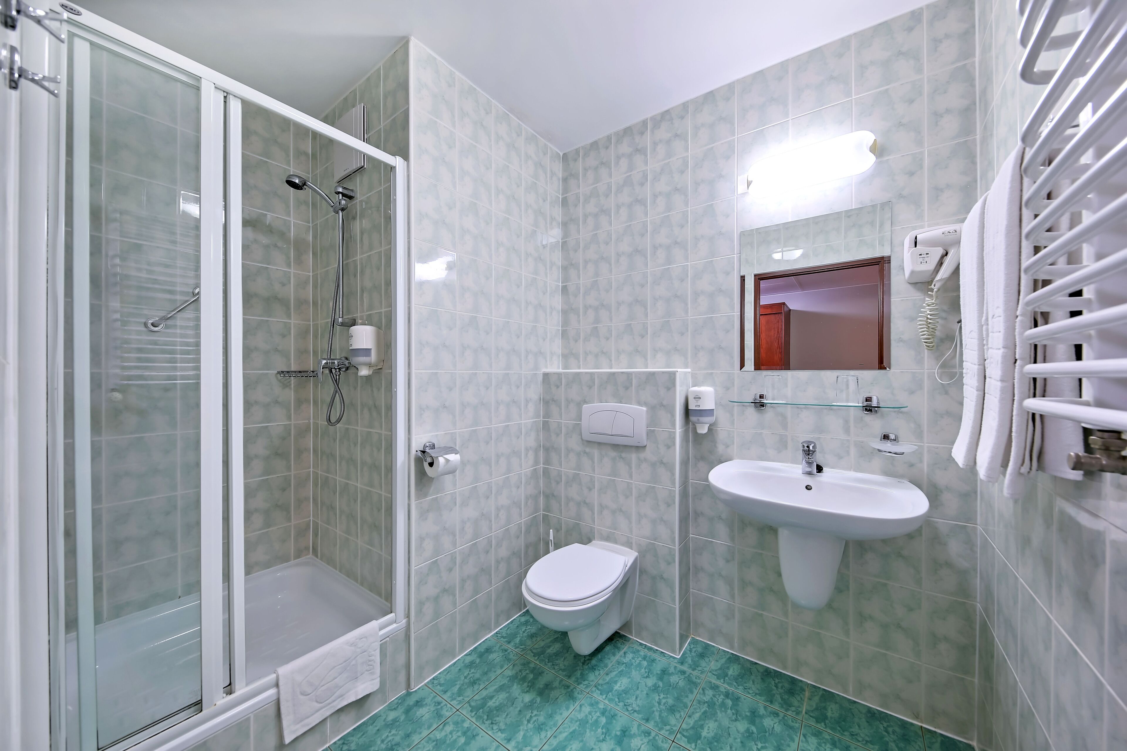 A bathroom with a glass-enclosed shower, a toilet, a sink, and a towel rack.