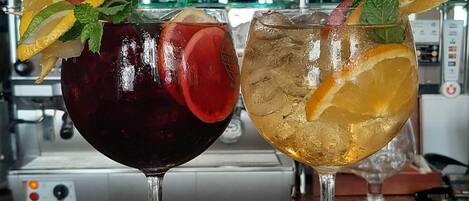 Dos cócteles sobre una barra con una variedad de botellas de licor al fondo.