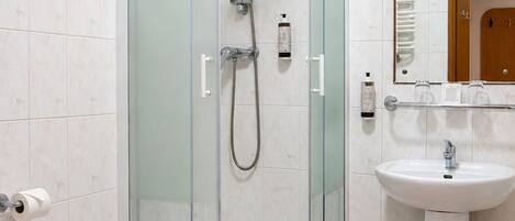 Un baño moderno con ducha de vidrio, lavamanos blanco pedestal y retrete.