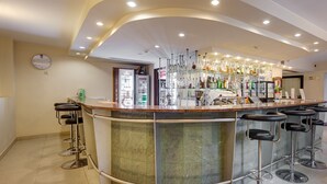 Una zona de bar con un mostrador curvo, varios taburetes y una amplia variedad de botellas y vasos.