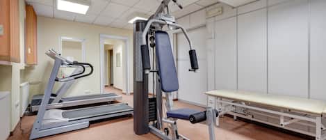 Een sportschool met loopbanden, een bank en krachttrainingsapparaten.