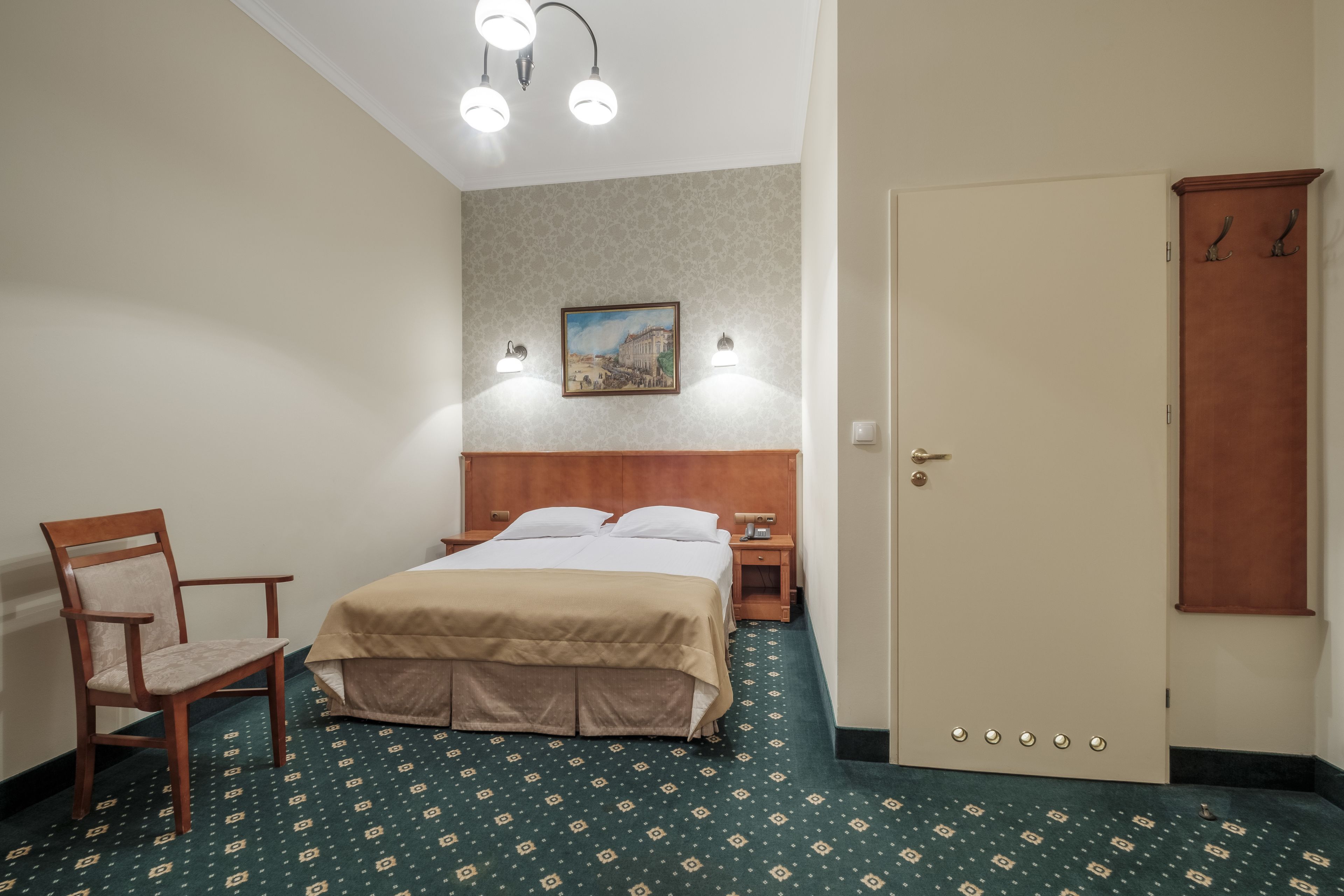Una habitación de hotel con cama, una silla, una mesita de noche y un armario.