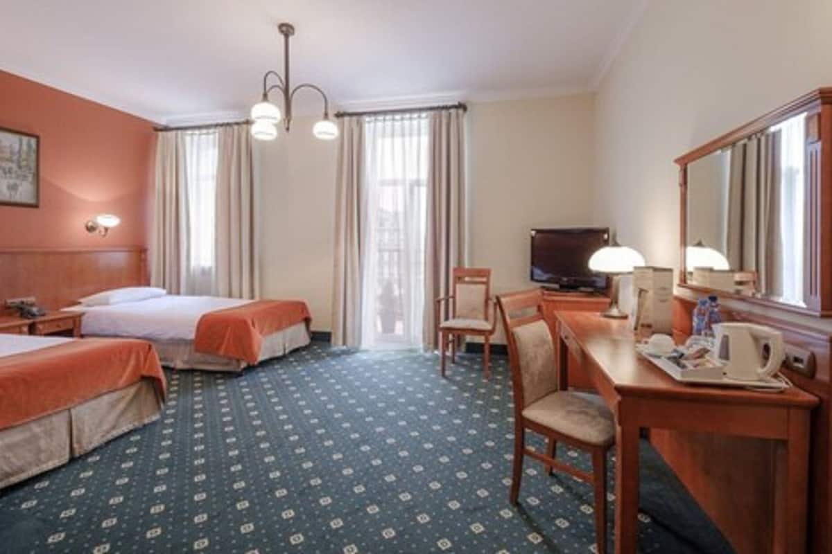 A hotel room with two beds, a desk with a chair, a television, and a large mirror.