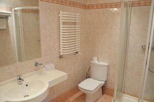 Une salle de bain équipée d’un lavabo, de toilettes et d’une douche à parois en verre.