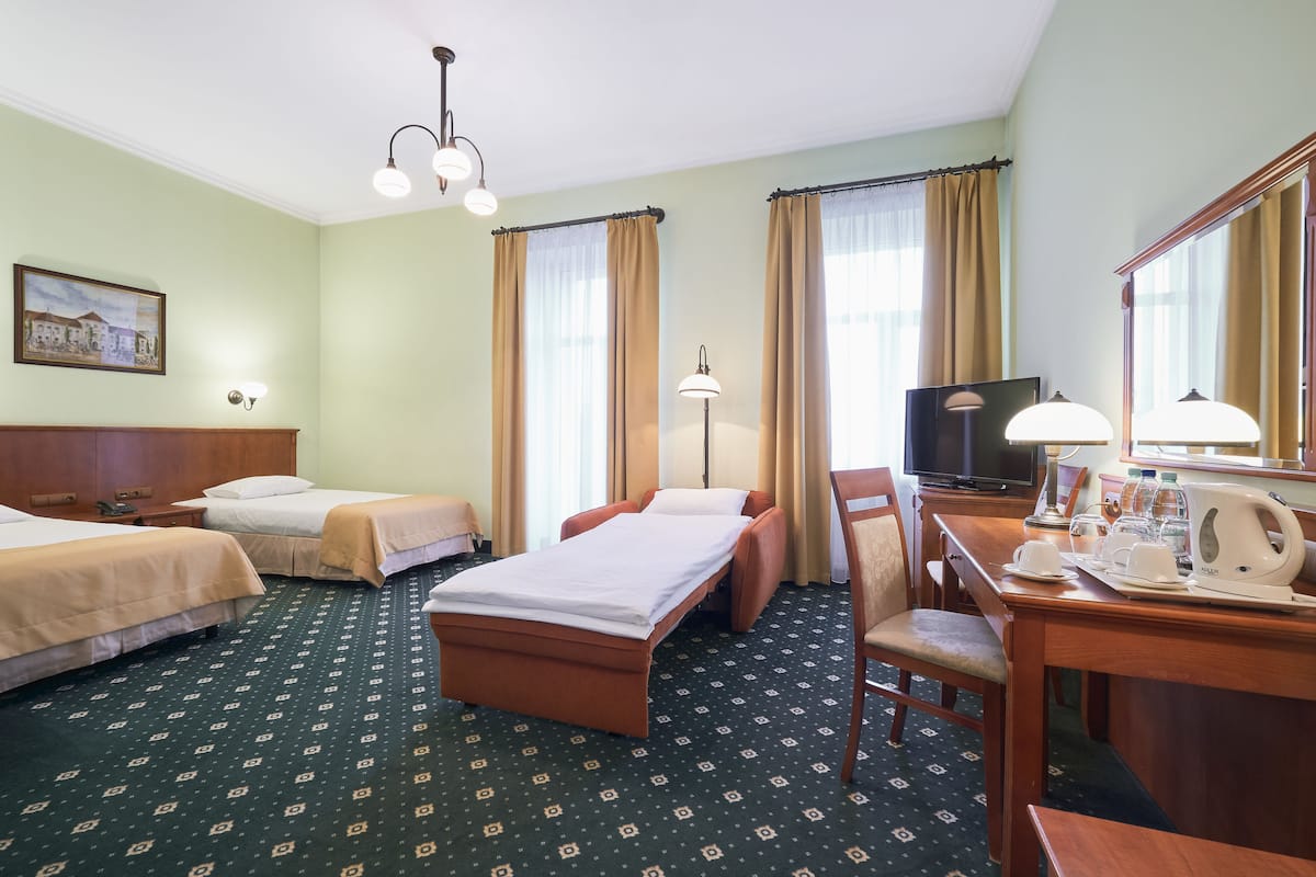 A hotel room with two beds, a desk with a chair, a television, and a coffee maker.