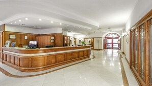 A spacious lobby with a curved reception desk, a polished marble floor, and a large arched doorway leading to the entrance. - Hotel Hetman (Warsaw)