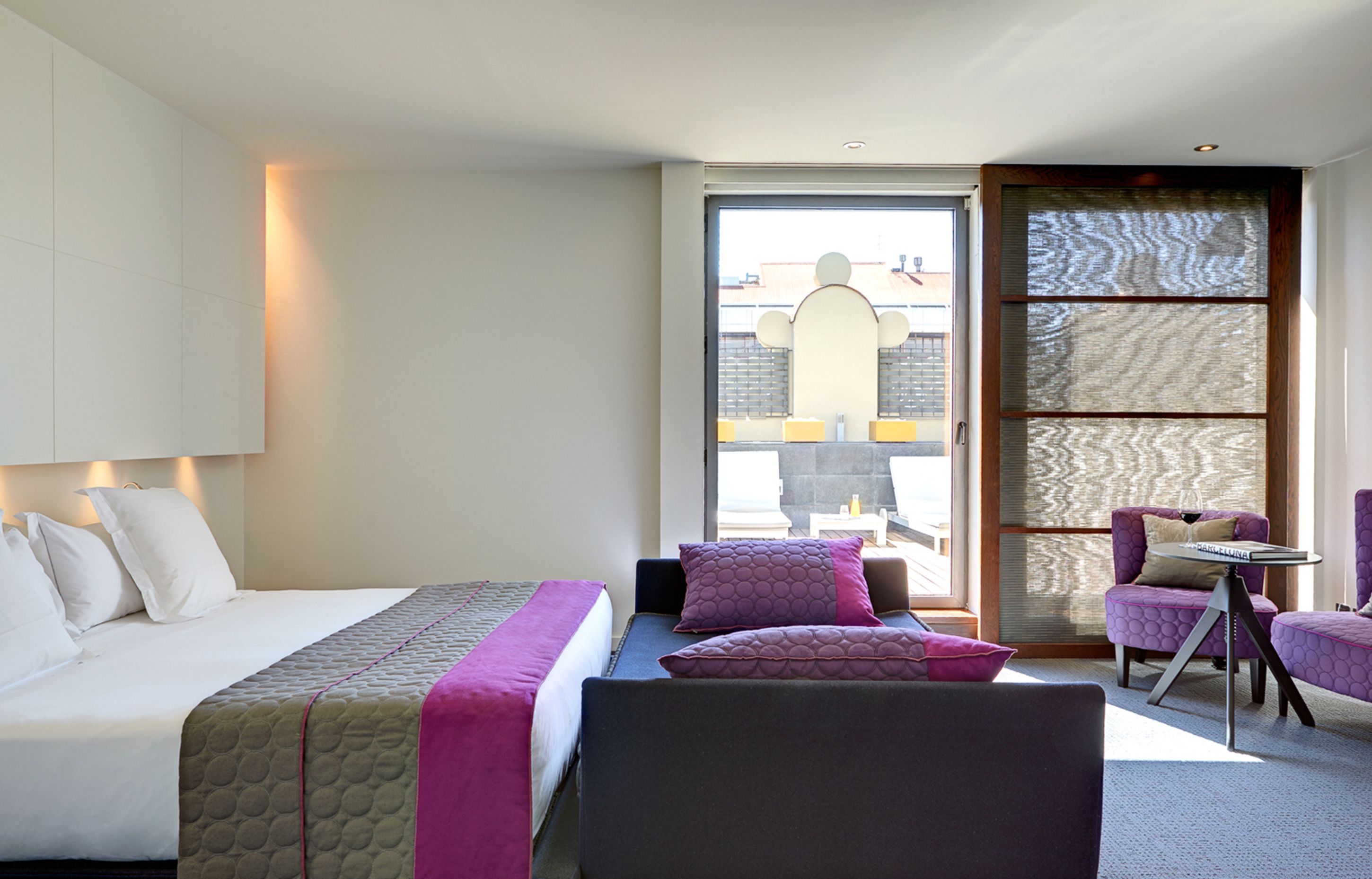 Ein modernes Hotelzimmer mit einem großen Bett, einem Schreibtisch und einem Stuhl. Ein Fenster bietet einen Blick hinaus.