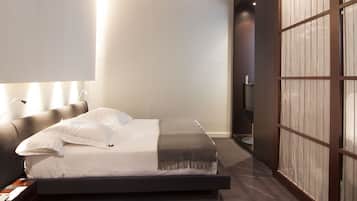 Une chambre d’hôtel moderne, équipée d’un lit, d’une table de chevet et d’une grande fenêtre avec des rideaux.