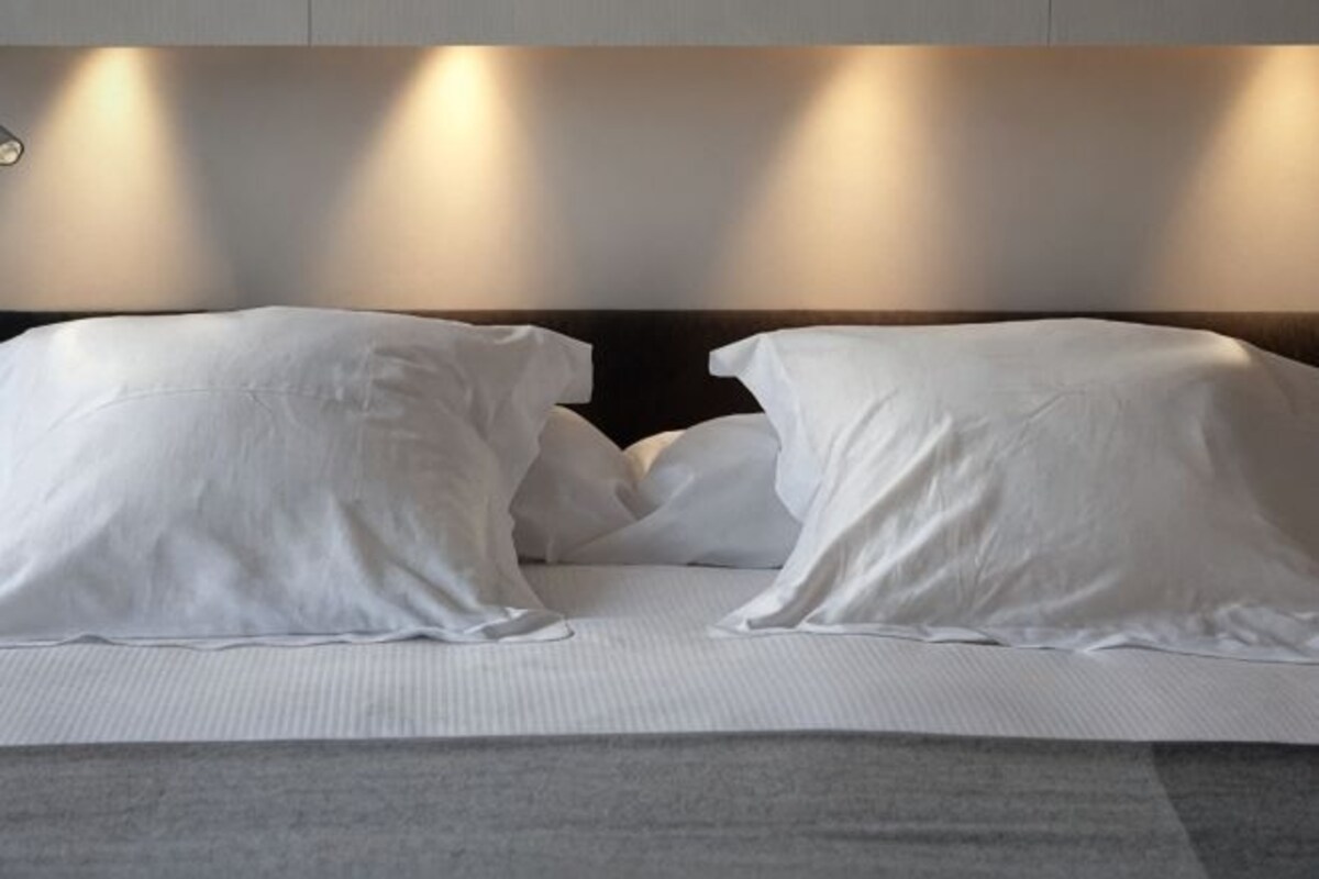 A bed with white bedding and a headboard with built-in lighting.