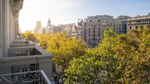A balcony with ornate railings overlooking a cityscape with historic buildings and a prominent tower.