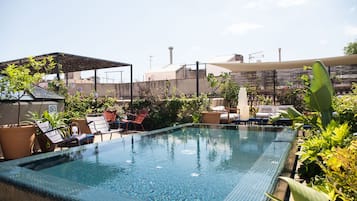 Una piscina infinita al aire libre con sillones de descanso y plantas en macetas.