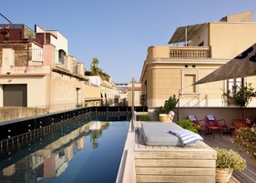 A pool with a wooden deck, lounge chairs, and potted plants.