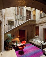 A spacious living area with a staircase, a sofa, a coffee table, and a vibrant rug.