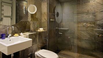A bathroom with a white sink, a toilet, and a glass-enclosed shower area.