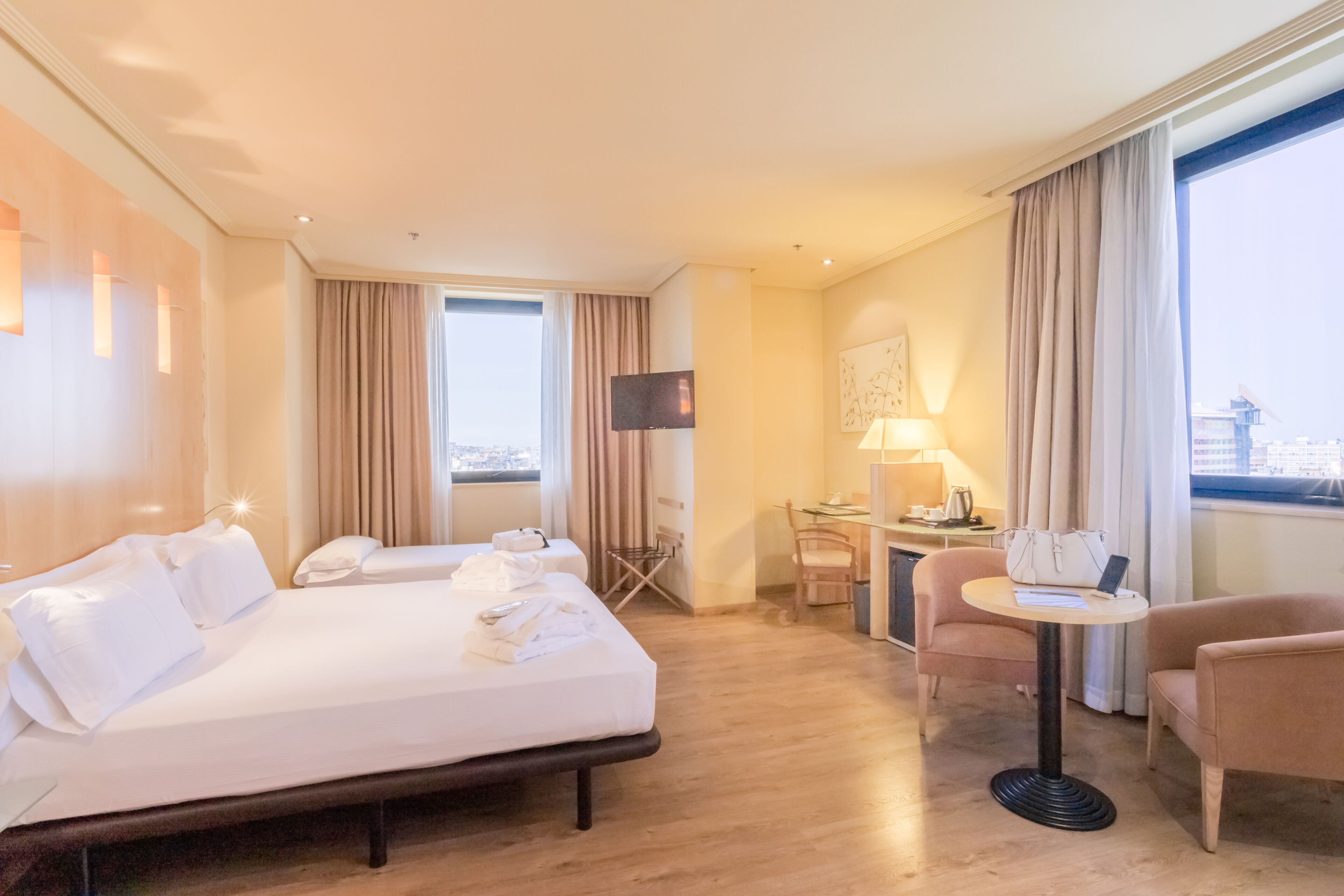 Habitación de hotel con una cama grande, un escritorio, una silla y vistas a la ciudad.