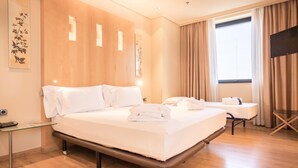 Una habitación de hotel con una cama grande, mesitas de noche, un escritorio y un televisor.