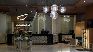 Un moderno vestíbulo de hotel con una recepción, un área de descanso e iluminación decorativa.