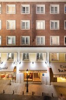 En hotellfasad med många fönster, ett kafé som heter ”Café Bon Appetit” på bottenvåningen och en skylt med texten ”Hotel Venida Gran Via”.