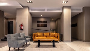 Un hall con un sofá, sillones y un extintor.
